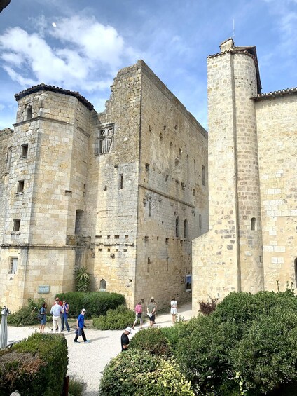 A historic stone castle with tourists walking in the courtyard. 2