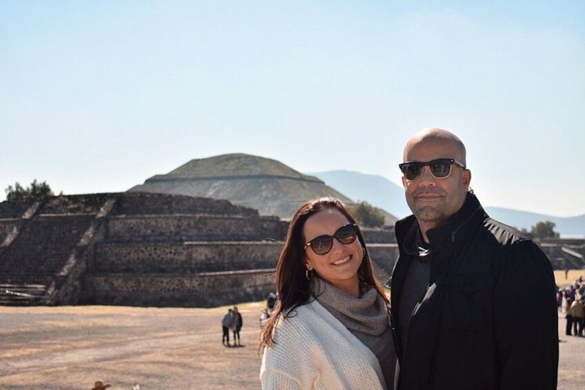 A person standing in front of a large ancient pyramid with a clear sky in the background. 4