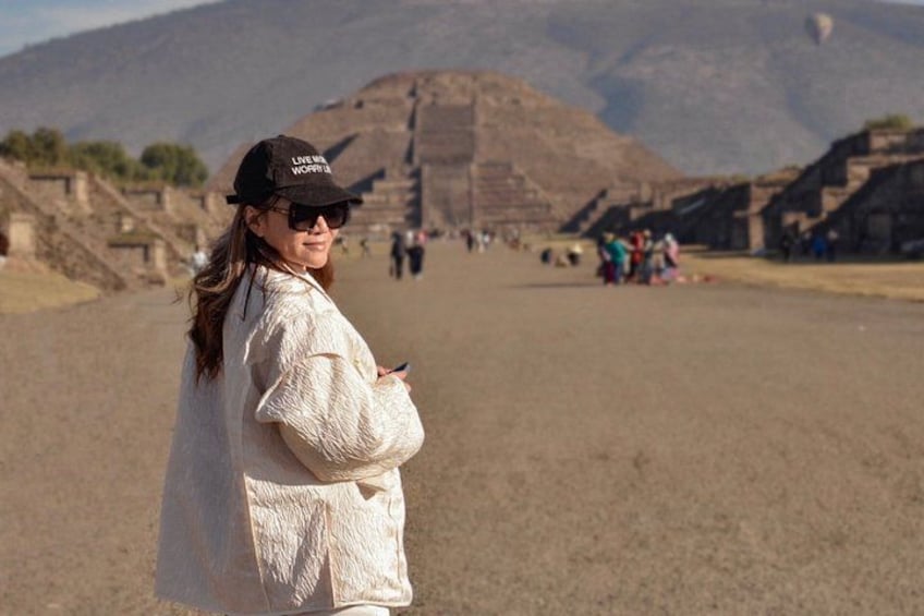 A person standing on a sandy area with pyramids in the background. 2