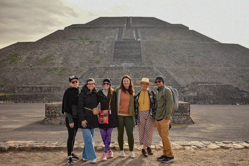 A group of people standing in front of a large pyramid-like structure. 3