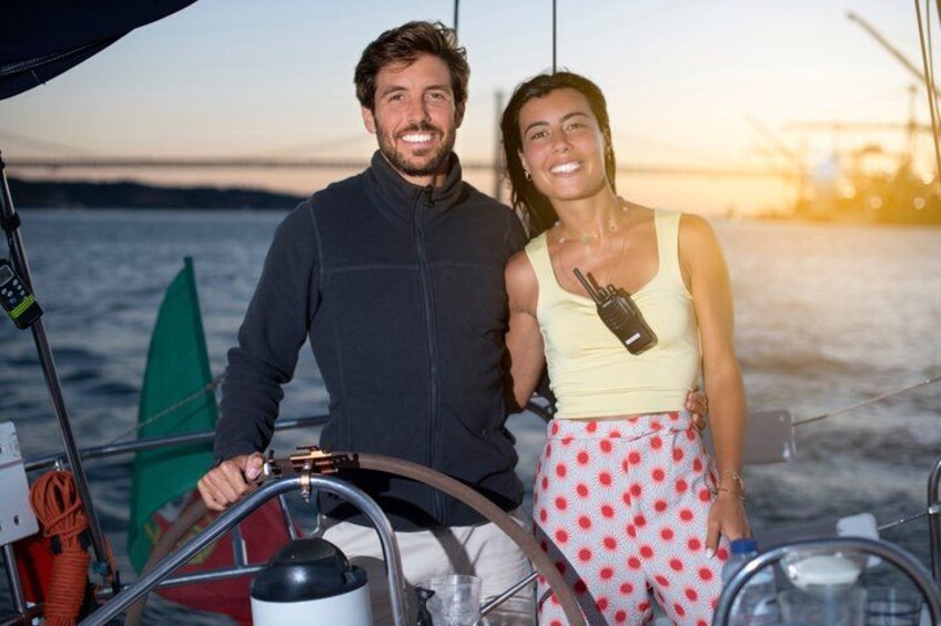 Una persona al timone di una barca, un'altra persona con un walkie-talkie, e una vela verde sullo sfondo. 3