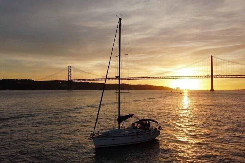 A sailboat on calm water with a bridge in the background during sunset. 5
