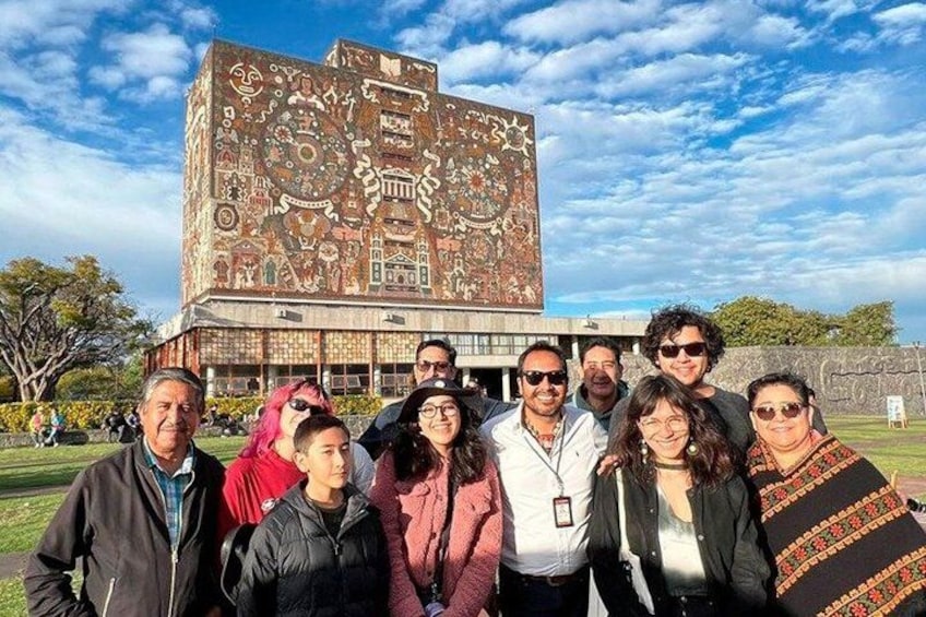 Un grupo de personas frente a un edificio con un mural grande y colorido. 4