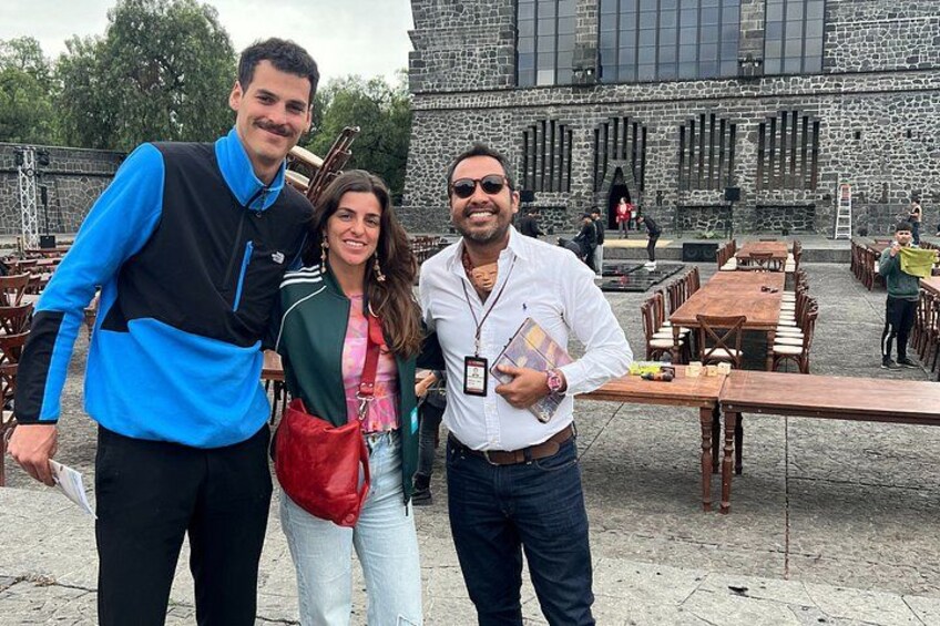 Tres personas frente a un edificio de piedra con patio. 5