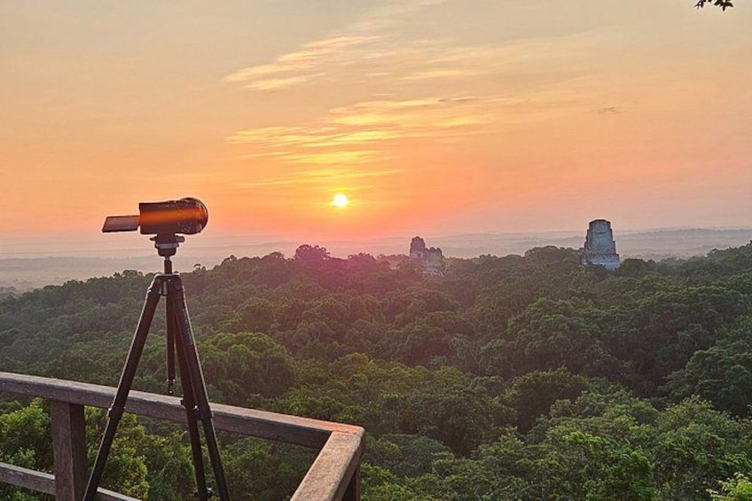 Un atardecer sobre un paisaje boscoso con un telescopio sobre un trípode. 2