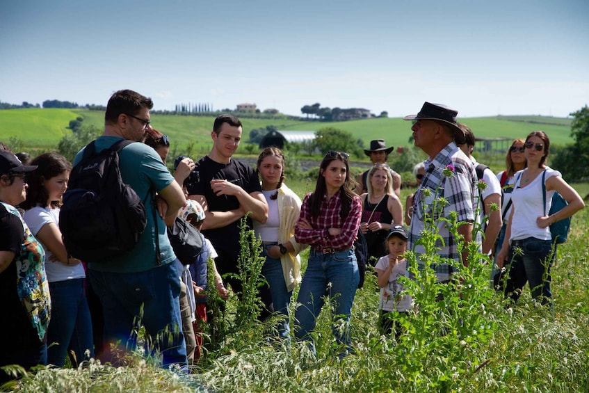 A group of people standing in a field with a rural landscape in the background. 1