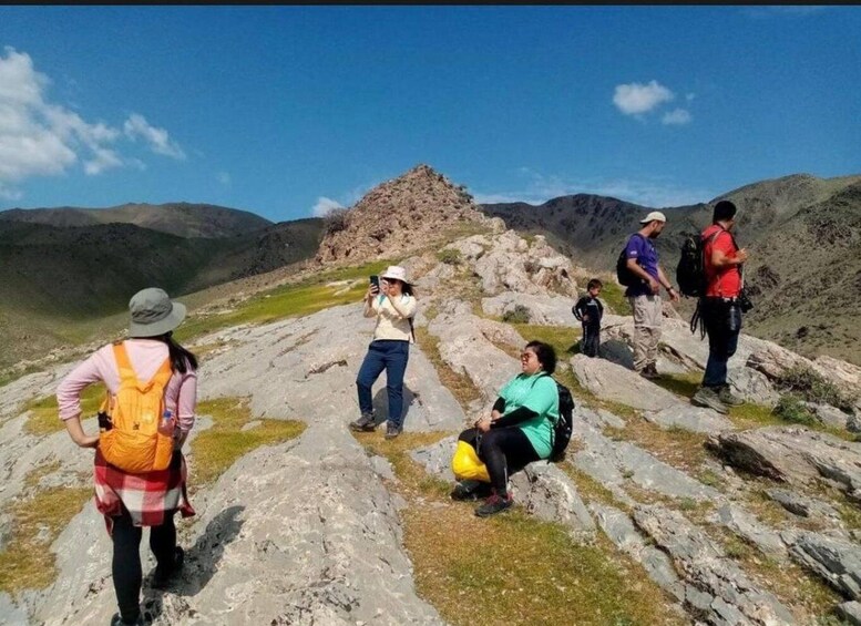 A group of hikers on a rocky mountain trail with a pyramid-shaped rock formation in the background. 2