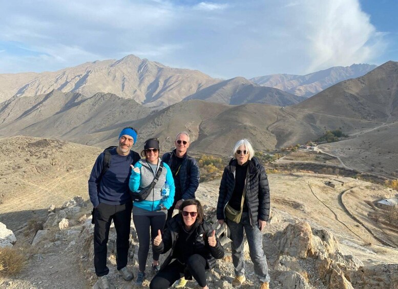 A group of people on a mountain trail with a desert landscape and mountains in the background. 1