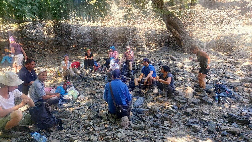 A group of people sitting on rocks in a rocky outdoor area. 5