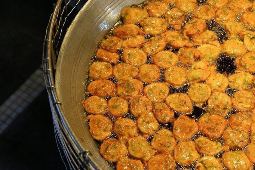 A large metal container filled with round, golden-brown fried items. 3