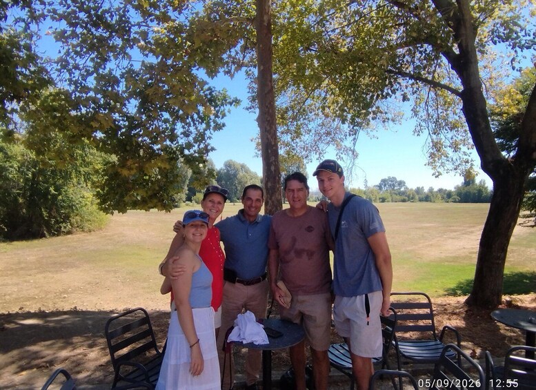 A group of people posing outdoors with trees and a grassy field in the background. 2