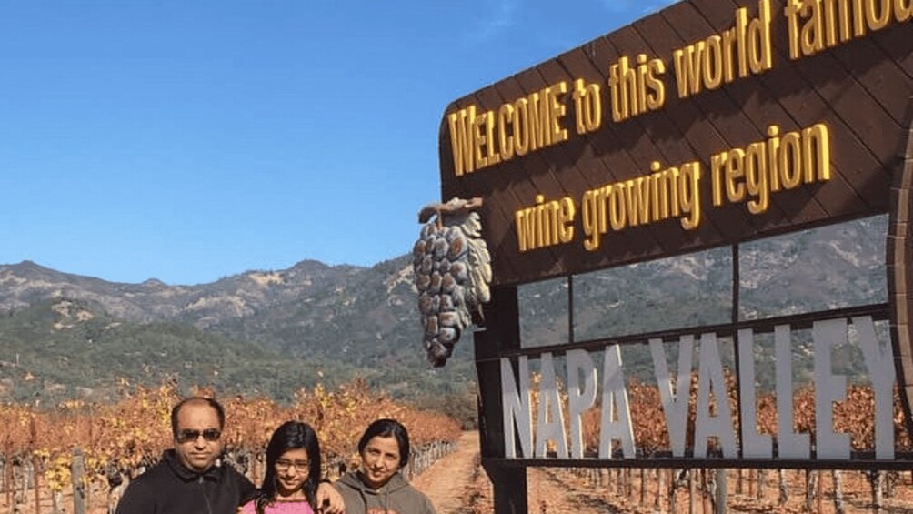 A sign welcoming visitors to Marapa Valley, a wine-growing region, with a vineyard and mountains in the background. 5