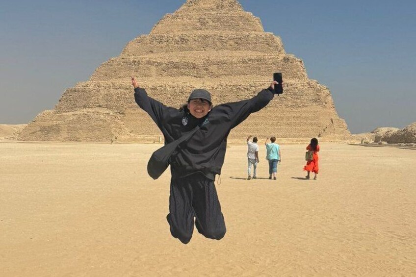 Eine Person springt vor einer Pyramide, im Hintergrund sind weitere Personen zu sehen. 5