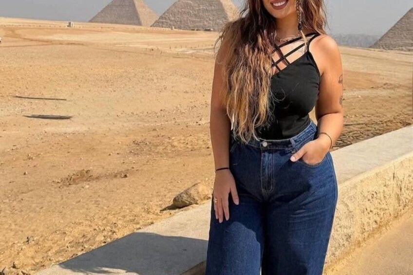 Eine Person steht in einer Wüste, im Hintergrund sind Pyramiden zu sehen. 3