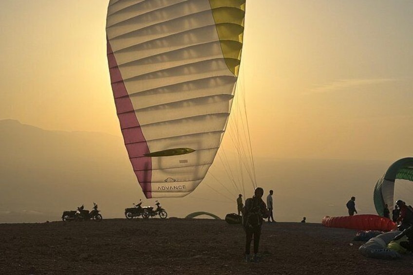 A person preparing to launch a kite on a beach with motorcycles and a dune buggy in the background. 3