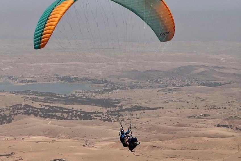 A person paragliding over a desert landscape with mountains in the background. 2