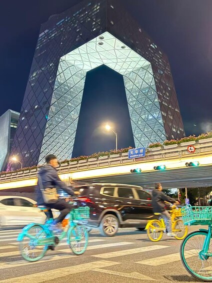 A busy street with cyclists and cars, a large modern building with a distinctive geometric design, and a sign indicating a height restriction. 5