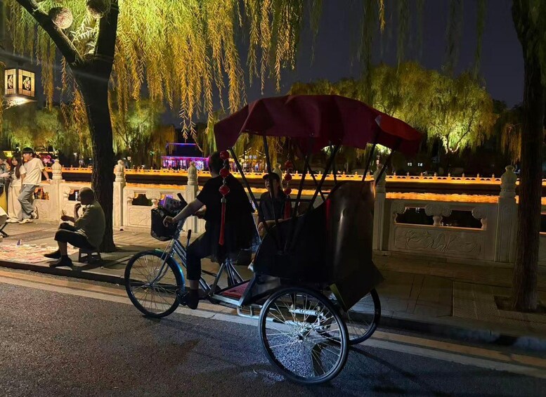 A person riding a traditional rickshaw at night. 3