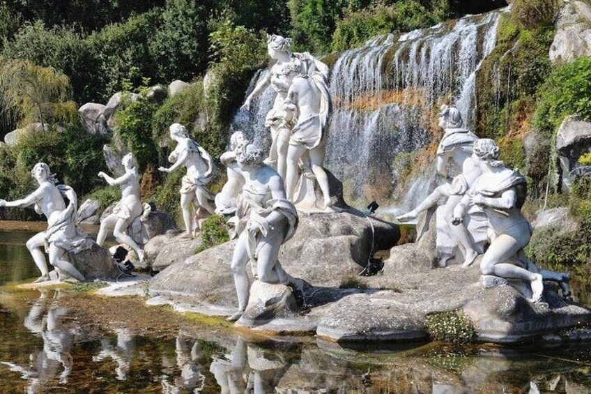 Una serie di statue in pietra classica accanto a una cascata. 5