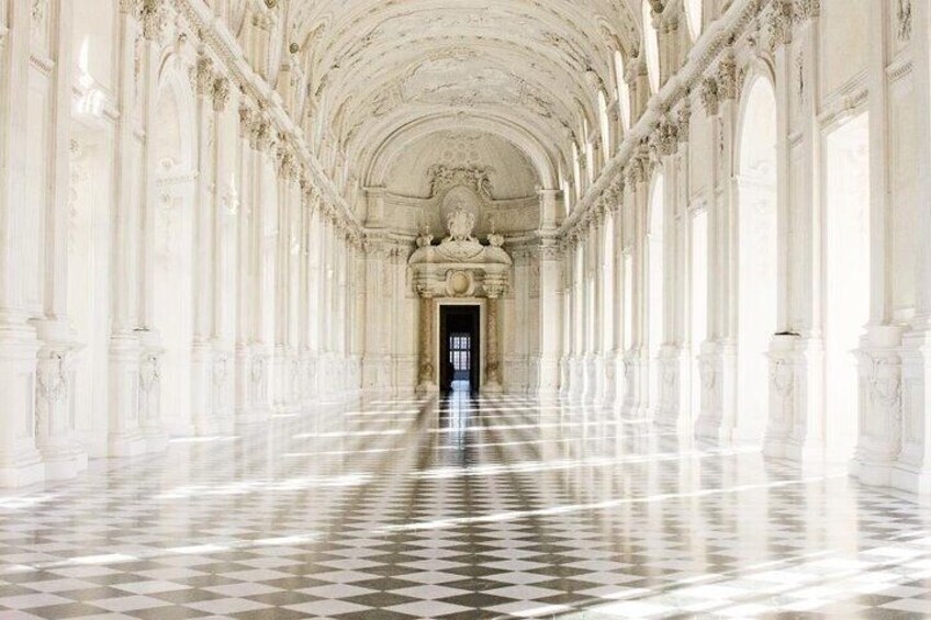 Un'imponente sala con colonne decorate e pavimento a scacchi, che conduce a un ingresso oscuro. 4