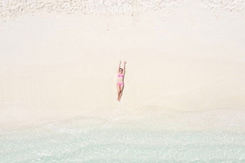 A person in a swimsuit mid-air above a sandy beach. 5