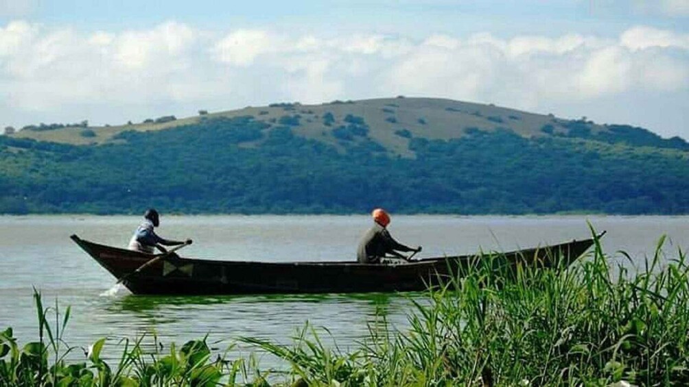 Two people in a boat on a calm lake with a hill in the background. 4
