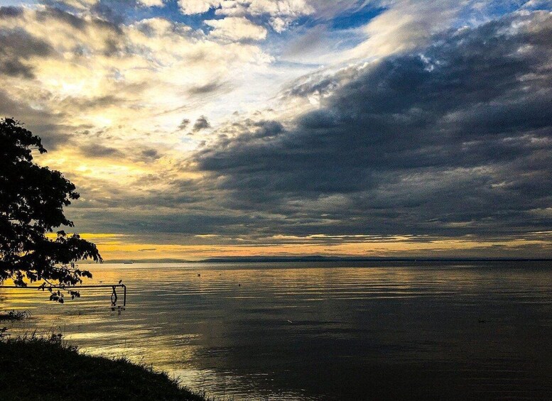 A sunset over a calm body of water with a silhouette of trees on the left. 2