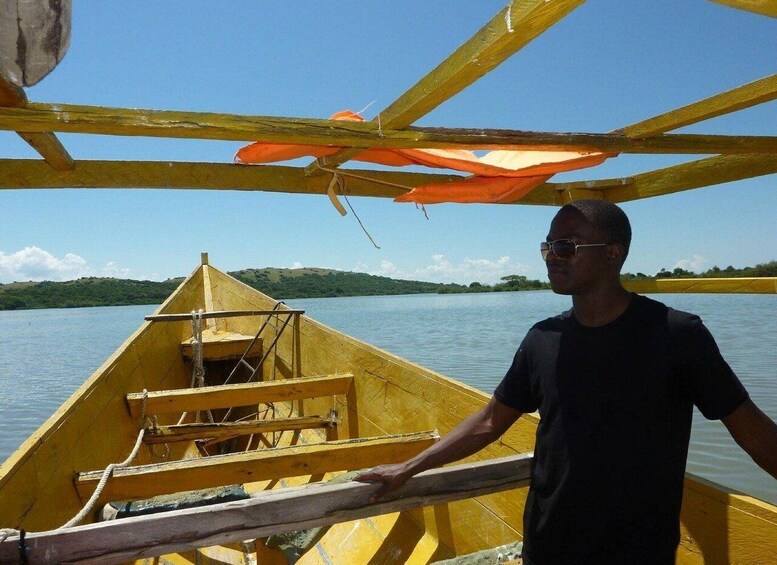 A man in a yellow boat on a calm lake with green hills in the background. 1