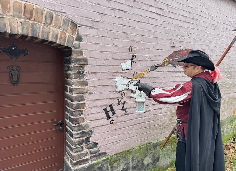 A person in historical costume painting on a brick wall. 2