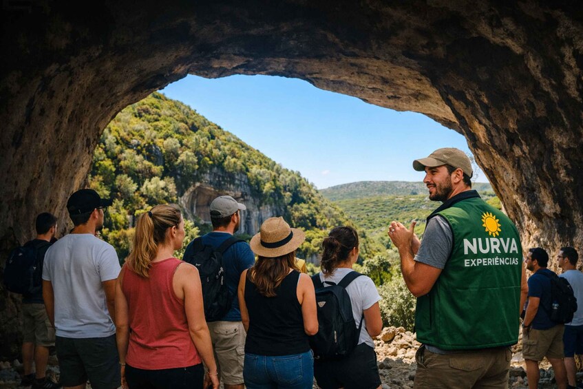 A group of people inside a cave with a view of a forested hillside. 4