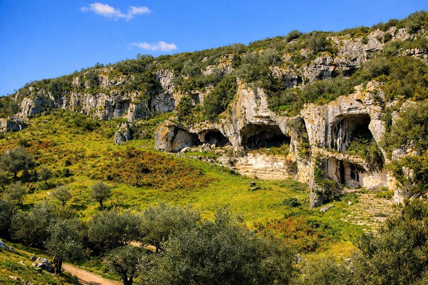 A mountainous landscape with rocky cliffs and cave openings. 5
