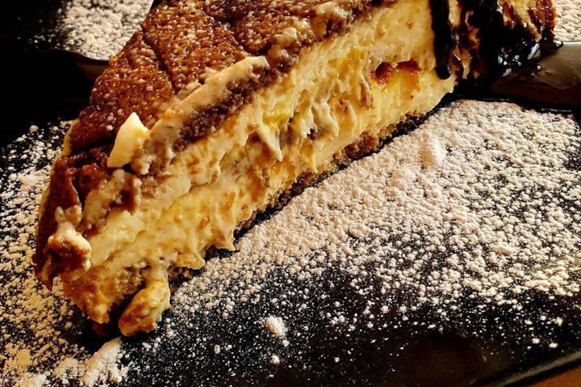 A slice of layered cake with powdered sugar on a dark surface. 2