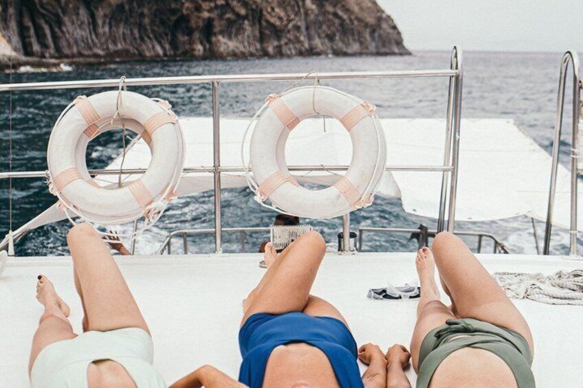 Two people relaxing on a boat with life rings hanging on the railing. 2
