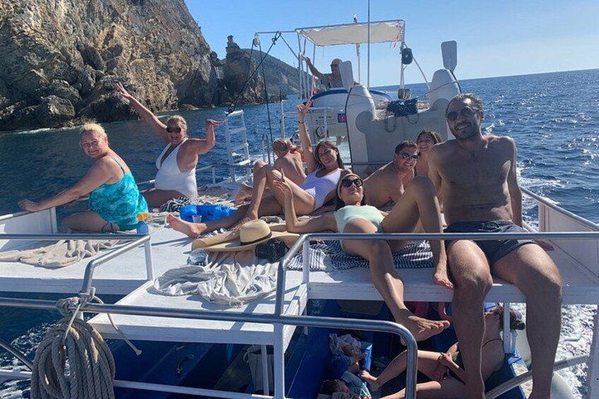 A group of people on a boat with rocky cliffs in the background. 3