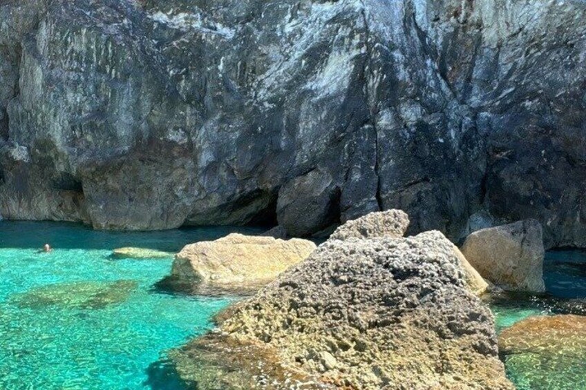 A rocky coastal landscape with clear turquoise water and large boulders. 4