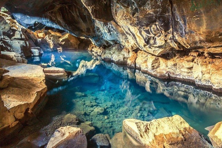 A cave with a clear water pool surrounded by rocky formations. 5