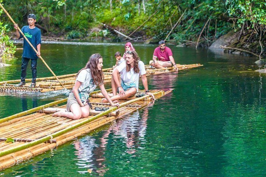 People sitting on bamboo rafts on a river surrounded by greenery. 1