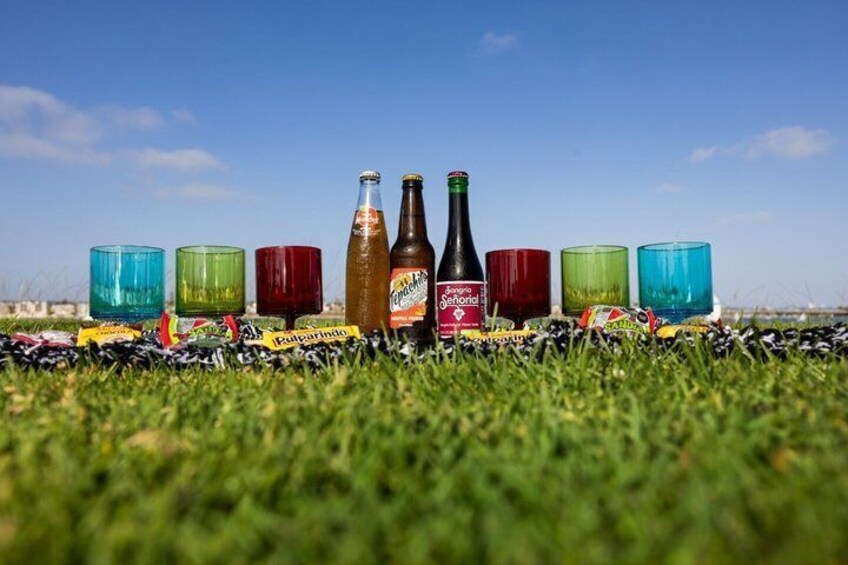 Un champ herbeux où des bouteilles et des verres de couleurs vives sont disposés en rangée. 3