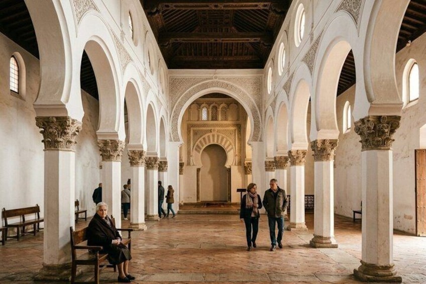 An interior with arches, columns, and a central walkway. 3