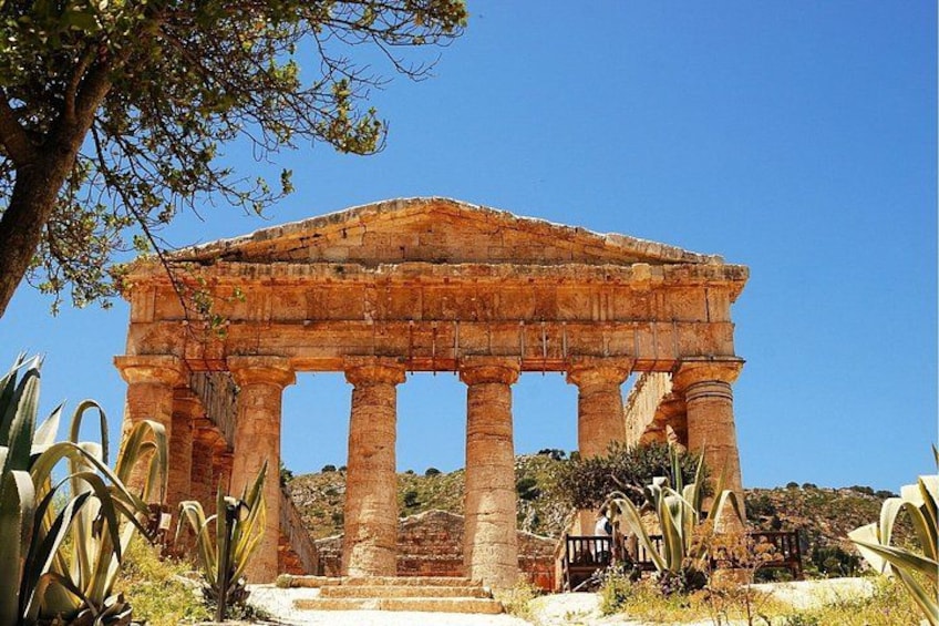 Une structure de pierre ancienne, dotée de colonnes, et entourée de végétation. 2