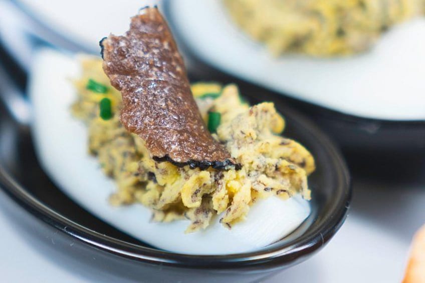 A plate of scrambled eggs with a piece of fried meat on top. 5