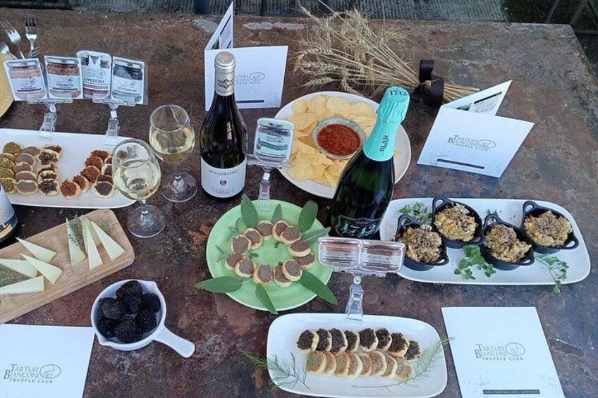 A table with various food items, a bottle of wine, and wine glasses. 1