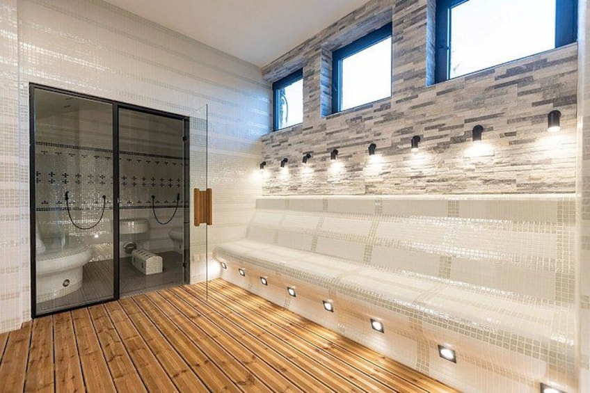 Un baño moderno con suelo de madera, cabina de ducha con paredes de cristal y un revestimiento de mosaicos. 4