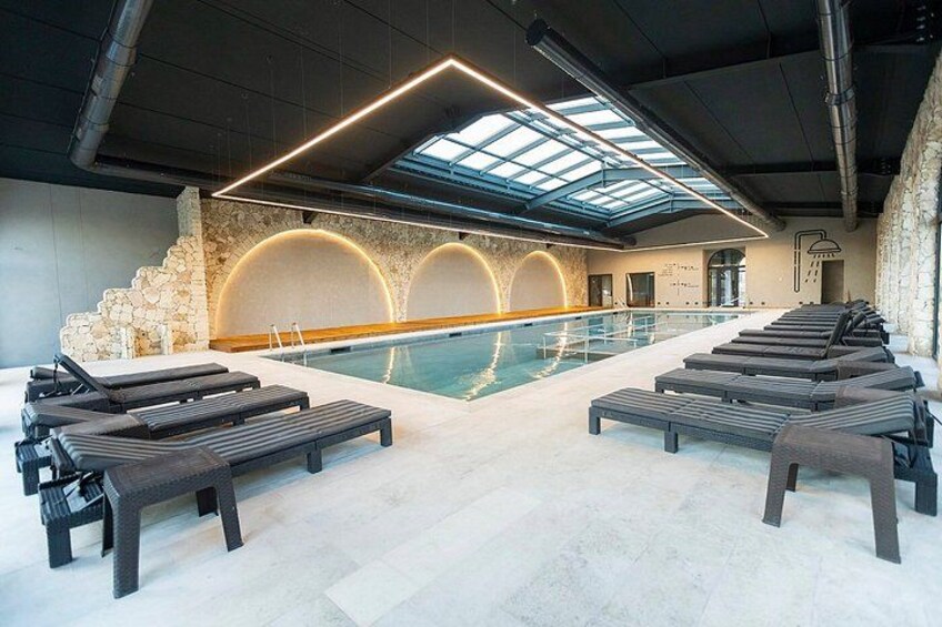 Una piscina interior con sillas de descanso, una pared de piedra y un tragaluz. 5