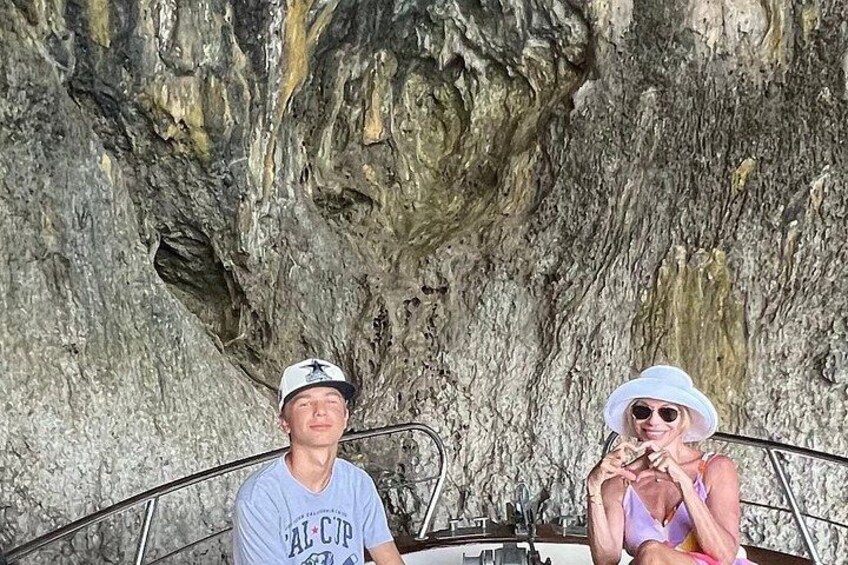 Two people on a boat with a rocky cliff in the background. 3