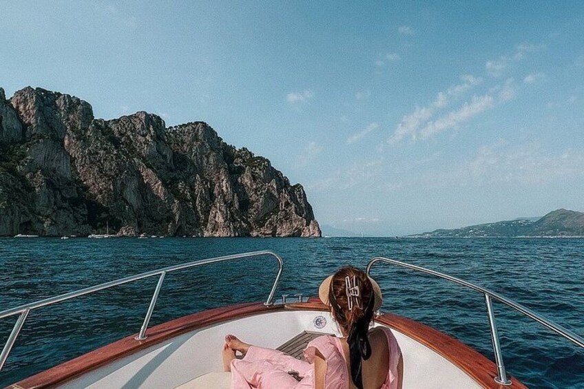 A boat on calm water with a rocky coastline in the background. 1