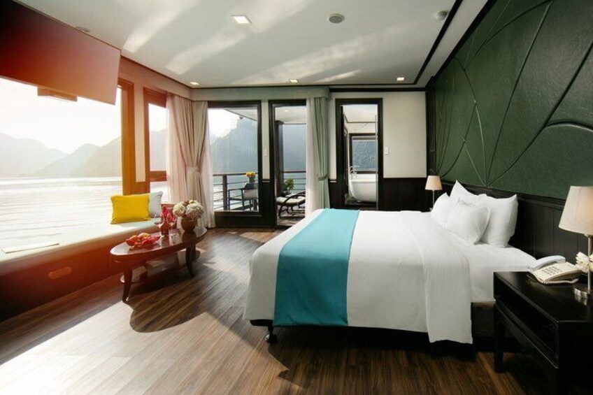 Een hotelkamer met een bed, een tafel met een vaas en uitzicht op zee. 1