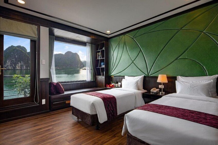 Een hotelkamer met twee bedden, een groot raam met uitzicht op zee en een groene, structuurrijke wand. 3