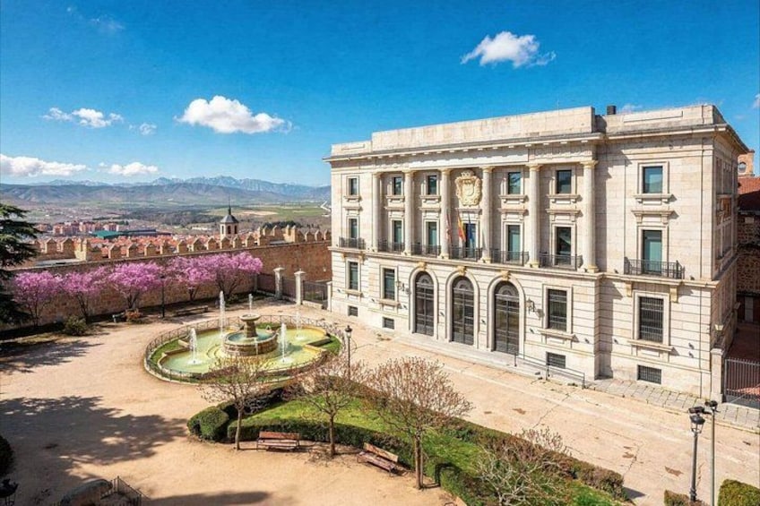 Un bâtiment historique doté d’une fontaine, entouré d’un jardin bien entretenu et surplombé d’un ciel d’un bleu éclatant. 2