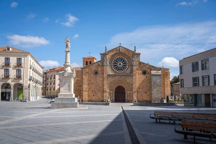 Une église historique dotée d’une grande fenêtre circulaire, d’une statue à l’entrée et d’une place publique avec des bancs. 5